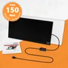 A black infrared desk heater with a power cord and plug, placed on an orange and white background. A small instruction booklet is also visible. Produktbild-Vorschau