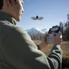 A person is flying a drone in a mountainous landscape. Produktbild-Vorschau