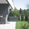 A garden storage box is placed on a patio next to a house, with trees and a lawn in the background. Podgląd zdjęcia produktu
