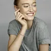 A woman wearing a grey t-shirt and a silver bracelet. Produktbild-Vorschau