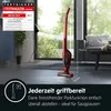 A red cordless vacuum cleaner is shown standing upright in a modern living room setting, with text overlays highlighting its features and test results. Produktbild-Vorschau