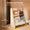A wooden children's bookshelf with books and fabric pockets, set against a light brown wall and rug. Produktbild-Vorschau