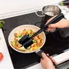 A person is using a black meat masher to stir vegetables in a frying pan on a stovetop. Produktbild-Vorschau
