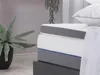 A close-up view of a mattress topper on a bed, with a plant in the background. Náhled obrázku produktu