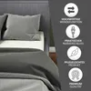 A close-up view of a bed with grey bedding, featuring icons and text highlighting product features. Náhled obrázku produktu