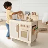 A young boy is playing with a wooden toy kitchen in a room. Anteprima dell’immagine prodotto