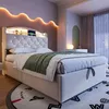 A bedroom scene with a bed, headboard, and decorative lighting. Náhľad obrázku produktu