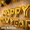 Golden balloons spelling out "Happy New Year" and "XXL Ballons" against a textured wall with sparkling effects. Anteprima dell’immagine prodotto