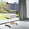 A multi-tiered drying rack with towels, blankets, and shoes on it, placed near a window with curtains. Produktbild-Vorschau