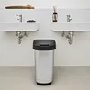 A bathroom scene with two sinks, a trash can, and decorative items. Voir les images du produit