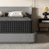 A mattress on a bed frame, with pillows and a bedside table in the background. Voir les images du produit