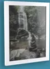 A framed picture of a waterfall and stacked stones. Produktbild-Vorschau