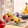 A kitchen counter with various fruits, a juicer, and a tray with juice. Náhľad obrázku produktu