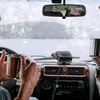 Two people in a car during a snowstorm, holding mugs and looking out the windshield. A car heater is visible on the dashboard. Náhľad obrázku produktu