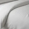 A close-up view of white bedding with subtle stripes. Produktbild-Vorschau