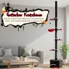 A cat tree is shown in a living room setting next to a sofa, with a decorative Halloween-themed graphic on the wall. Produktbild-Vorschau