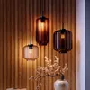 Three pendant lights hang against a wood-paneled wall, with a decorative branch in a vase in the foreground. Produktbild-Vorschau