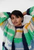 A woman wearing a colorful striped sweater and cardigan. Produktbild-Vorschau