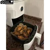 An air fryer with a basket of cooked chicken wings inside, placed on a countertop. Produktbild-Vorschau