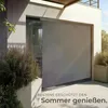 A modern patio with a large roller blind covering a glass door, with plants in concrete planters. Náhled obrázku produktu