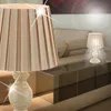 Two table lamps are shown in a living room setting, one in the foreground and another in the background on a coffee table. Produktbild-Vorschau