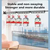 A wall-mounted retractable clothes drying rack is shown with several large bottles of water hanging from it to demonstrate its strength and stability. The background shows a blurred cityscape and a body of water. Produktbild-Vorschau