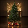 A decorated Christmas tree with gifts and candles on the floor, with bokeh lights in the background. Produktbild-Vorschau