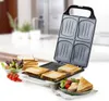 A sandwich maker is open, showing four sandwich slots. To the side, there are prepared sandwiches, a bowl of salad, and a stack of bread slices. Produktbild-Vorschau