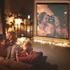 A family is watching a movie on a projector screen in a dimly lit room, decorated with fairy lights. Voir les images du produit