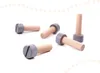 Several wooden toy bolts with gray heads are scattered on a white surface, with a decorative dotted border at the top and bottom. Podgląd zdjęcia produktu