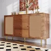 A wooden sideboard with rattan doors and gold legs, decorated with vases of flowers and bottles of wine. Voir les images du produit