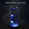 A jellyfish lamp with colorful lights is displayed in a dark room, with a woman in the background looking at it. Anteprima dell’immagine prodotto