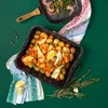 A baking tray filled with roasted vegetables and a frying pan with asparagus and bacon are placed on a green surface, with kitchen towels and rosemary sprigs. Produktbild-Vorschau