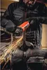 A person is using an angle grinder to cut a metal bar held in a vise, with sparks flying. Podgląd zdjęcia produktu