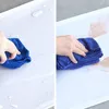 A split image showing a hand cleaning a white surface with a blue cloth. The left side shows the cloth wiping away water, and the right side shows it wiping away some brown dust or dirt. Náhľad obrázku produktu