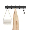 A black wall-mounted coat rack with a white handbag, a beige jacket, and keys hanging on it. Produktbild-Vorschau