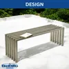 A modern metal bench is placed on a white outdoor patio with greenery in the background. Produktbild-Vorschau