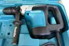 A Makita rotary hammer drill is shown inside its blue plastic carrying case. Produktbild-Vorschau