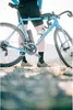 A person standing next to a bicycle on a rocky surface. Podgląd zdjęcia produktu