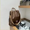 Brauner Stoffrucksack mit hellbraunen Trägern und silberfarbenem Logo, ausgestellt auf einem Holzregal Anteprima dell’immagine prodotto