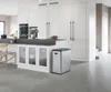 A modern kitchen with white cabinets and a stainless steel trash can. Voir les images du produit