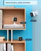 Two small security cameras are shown on shelves, one on a bracket and one without a stand. Text overlays describe features and placement options. Produktbild-Vorschau