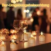 A table setting with wine glasses and LED tea lights, with blurred people in the background. Produktbild-Vorschau