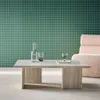 A modern living room setting with a coffee table in the foreground and a chair in the background. Produktbild-Vorschau