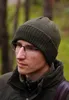 A man wearing a green beanie and glasses in an outdoor setting. Voir les images du produit