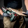 A person wearing work gloves and tan pants is using a green and black Metabo cordless jigsaw to cut a piece of wood. Voir les images du produit