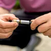 A person's hands are shown assembling a metal nozzle with a black hose attachment. Produktbild-Vorschau