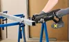 A person is using a cordless reciprocating saw to cut a metal pipe supported by sawhorses. Produktbild-Vorschau
