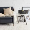 A modern living room with a sofa, a small side table with a stereo system, and artwork in the background. Produktbild-Vorschau