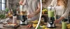 A split image showing two different people using a blender to make smoothies in a kitchen setting. Produktbild-Vorschau